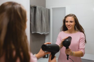 Saçlarını banyoda kurutan kadın.