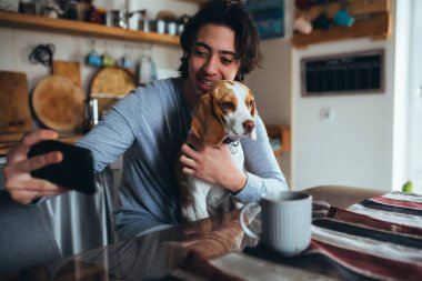 Köpeğiyle evde fotoğraf çeken genç bir adam, sabah sahnesi.