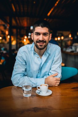 Kafeteryada kahve içen genç adam.