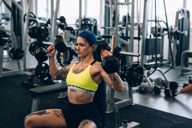 Dövmeli kadın spor salonunda çalışıyor.