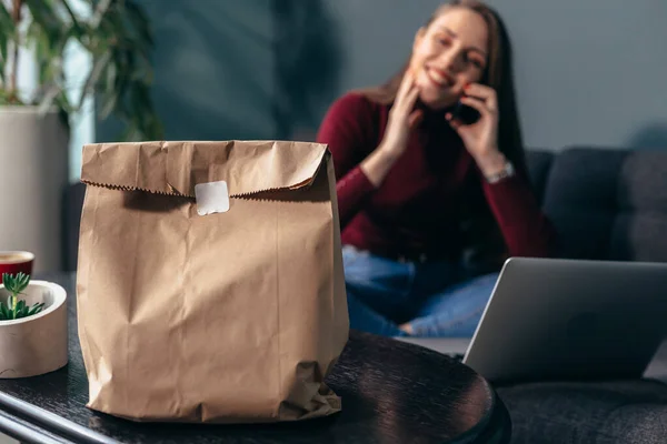 把食物放进纸袋里 女人用手提电脑做背景 — 图库照片