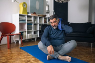 Orta yaşlı adam evinde egzersiz yapıyor.