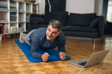 Orta yaşlı adam evinde egzersiz yapıyor.