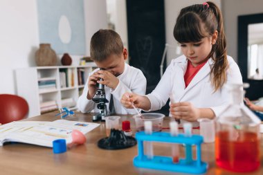 Çocuklar evde mutfak malzemeleriyle kimyasal deneyler yapıyorlar.