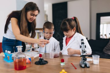 Çocuklar anneleriyle evde mutfak malzemelerinden kimyasal deneyler yapıyorlar.