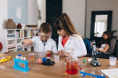 Çocuklar evde mutfak malzemeleriyle kimyasal deneyler yapıyorlar.