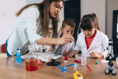 Anne ve çocukları evde kimyasal deneyler yapıyorlar.