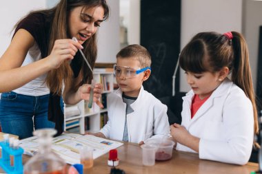 Anne ve çocukları evde kimyasal deneyler yapıyorlar.