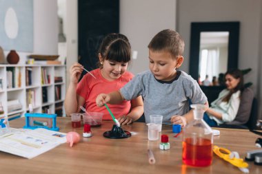 Erkek ve kız kardeş evde kimyasal deneyler yapıyorlar.