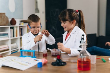 Erkek ve kız kardeş evde kimyasal deneyler yapıyorlar.