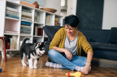 Kadın, oturma odasındaki kanepede otururken köpeğiyle kahvaltı yapıyor.