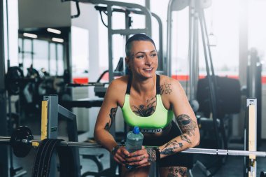 Dövmeli kadın spor salonunda çalışıyor.