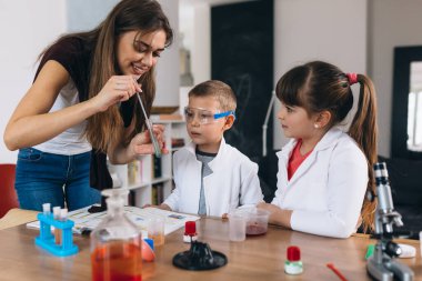 Anne ve çocukları evlerinde kimyasal deneyler yapıyorlar.