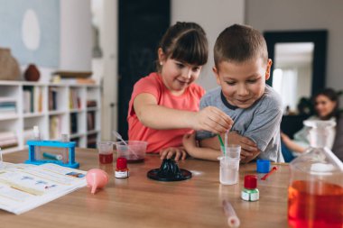 Erkek ve kız kardeş evde kimyasal deneyler yapıyorlar.