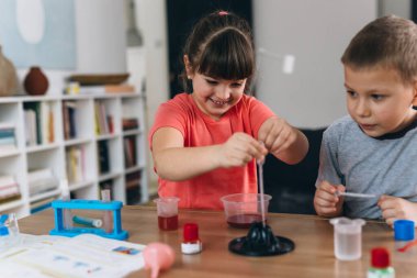 Erkek ve kız kardeş evde kimyasal deneyler yapıyorlar.