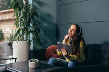 Kadın oturma odasında müzik dinliyor.
