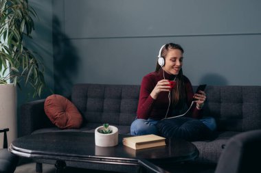 Kadın oturma odasında müzik dinliyor.