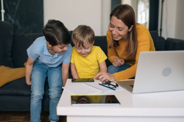 Anne ve çocukları evde cep telefonu kullanıyor.