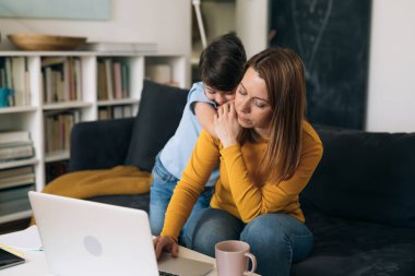 Annem evde çalışıyor. Oğlu ona sarılarak destek oluyor.
