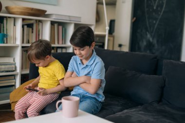 Çocuklar evde cep telefonuyla oyun oynuyorlar.