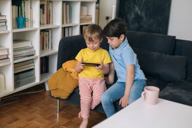 Çocuklar evde cep telefonuyla oyun oynuyorlar.