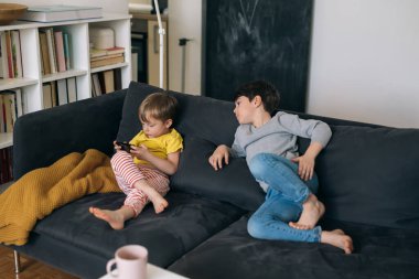 Çocuklar evde cep telefonuyla oyun oynuyorlar.