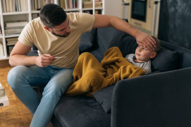 Baba hasta oğlunun ateşini ölçer.