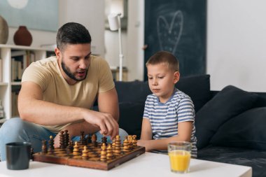 Baba oğluyla evde satranç oynuyor.
