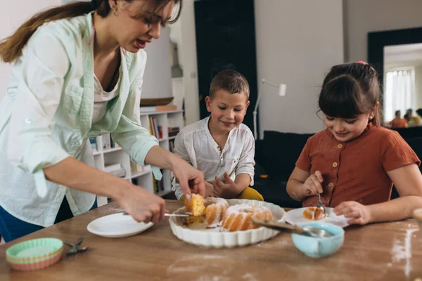 mother and kids eating cake at home