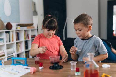 Erkek ve kız kardeş evde kimyasal deneyler yapıyorlar.