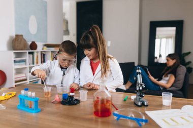 Erkek ve kız kardeş evde kimyasal deneyler yapıyorlar.