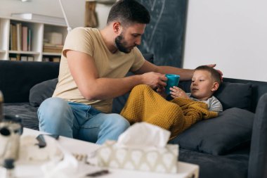 Baba hasta oğluna bir fincan sıcak çay verir.