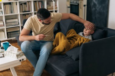 Baba hasta oğluna ısı ölçer.