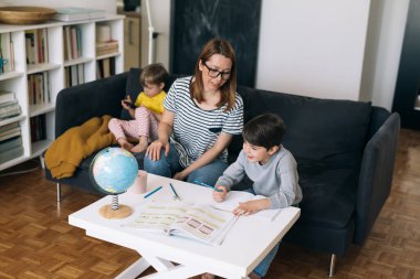 Anne ve oğlu evde ödev yapıyor.