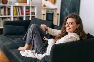 Kadın sabah kahvesi içiyor ve evde dijital masa kullanıyor.