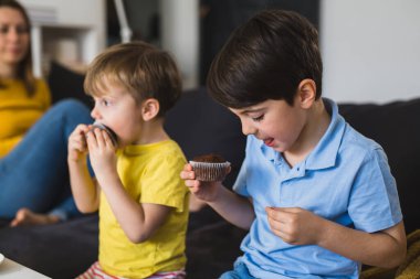 Çocuklar evde çikolatalı kek yiyorlar.