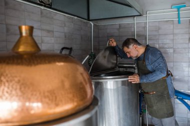 Mini zanaat bira fabrikasında çalışan orta yaşlı bir adam.