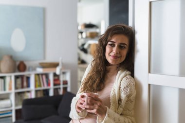 Kadın evinde dinleniyor, sabah kahvesini içiyor.