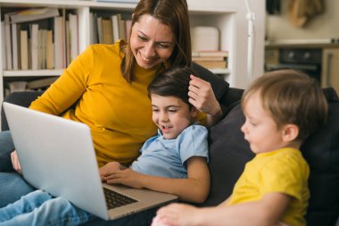 Anne ve oğulları evde dizüstü bilgisayar kullanıyorlar.