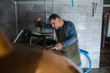 Mini zanaat bira fabrikasında çalışan orta yaşlı bir adam.