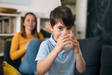 Küçük çocuk evde süt içiyor.