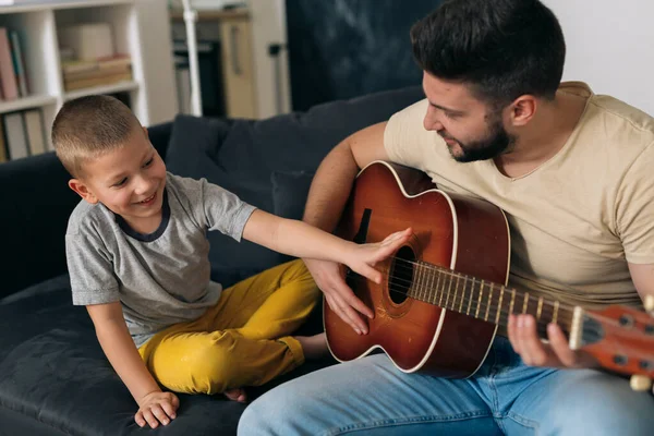 Baba ve oğul evde eğleniyorlar. Akustik gitar çalıyorlar.