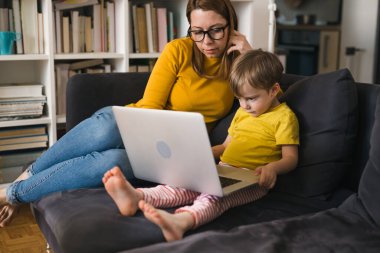 Anne çocuğuyla dizüstü bilgisayar kullanıyor.
