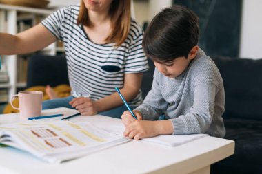 Anne oğlunun ödevlerine yardım eder.