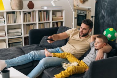 Baba oğul TV 'de maç izliyorlar.