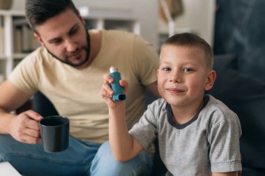 Küçük çocuk evde astım pompası kullanıyor.