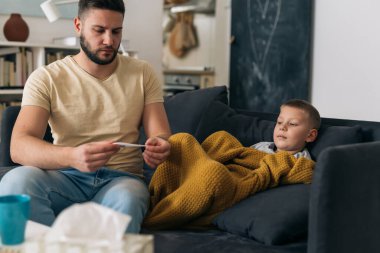 Çocuğun bacası var. Baba ateşini ölçüyor.