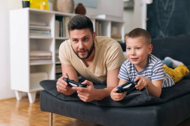 baba ve oğul evde video oyunu oynuyorlar.