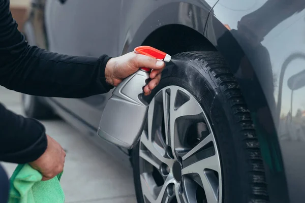 Araba yıkama servisinde araba lastiklerini temizleyen adam.