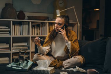 Kadının bacası var. Doktor çağırmak istiyor. Evindeki kanepede oturuyor.